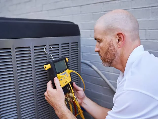 Technician using a diagnostic instrument to inspect an outdoor air conditioner