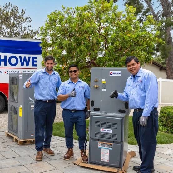 HVAC professionals standing beside furnace and air conditioning equipment